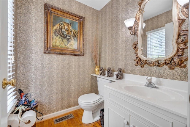 bathroom featuring wallpapered walls, toilet, visible vents, vanity, and wood finished floors