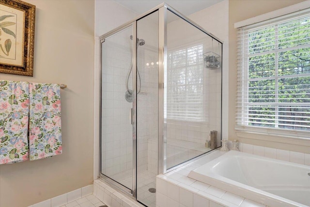 bathroom featuring a stall shower, a healthy amount of sunlight, and a bath