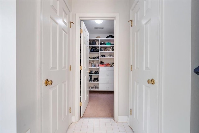 hall with light colored carpet, light tile patterned floors, and visible vents