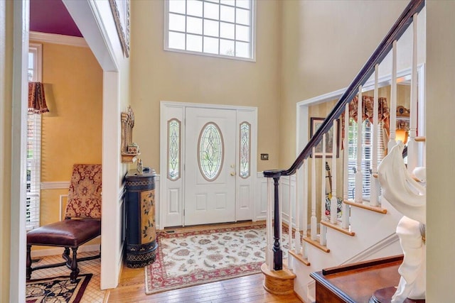 foyer with stairway, a towering ceiling, a wealth of natural light, and wood finished floors