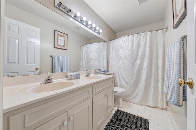 bathroom featuring toilet, tile patterned floors, double vanity, and a sink