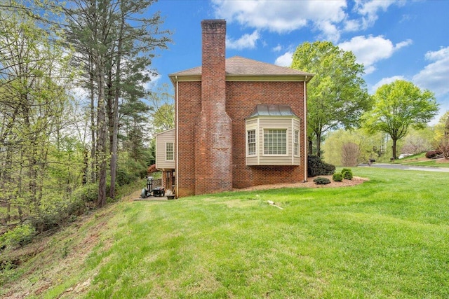 view of property exterior featuring a yard, brick siding, and a chimney