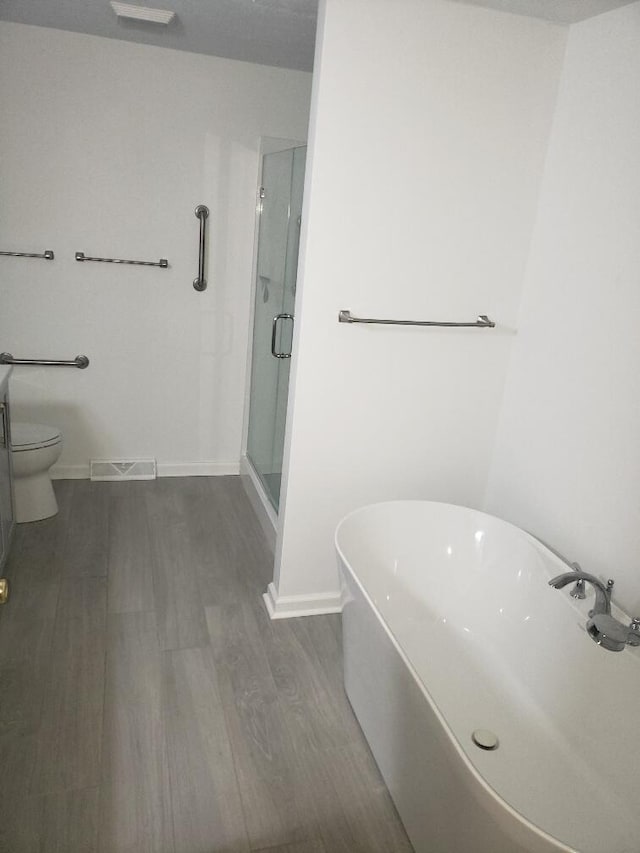 full bath with a shower stall, wood finished floors, visible vents, baseboards, and a freestanding tub