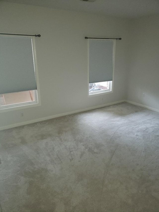 carpeted empty room featuring plenty of natural light and baseboards