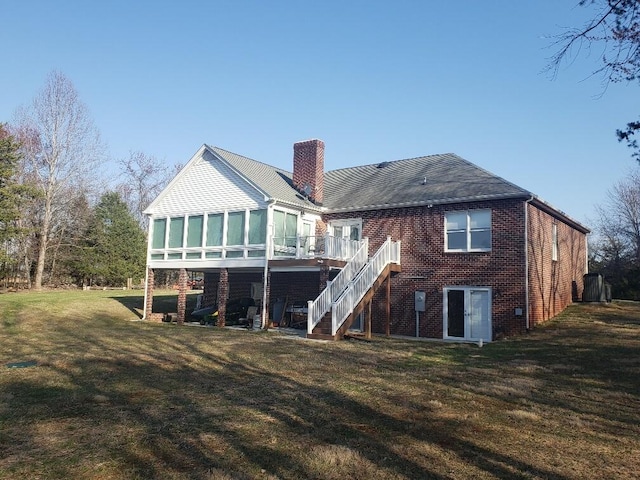 rear view of property with a chimney, stairs, a wooden deck, a lawn, and brick siding