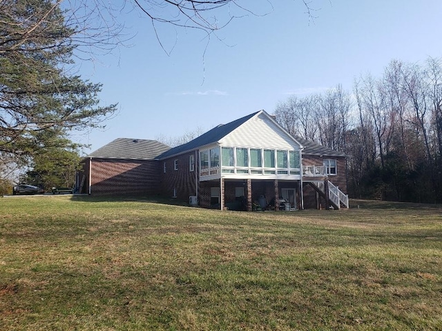 back of property featuring a sunroom, a yard, and stairway