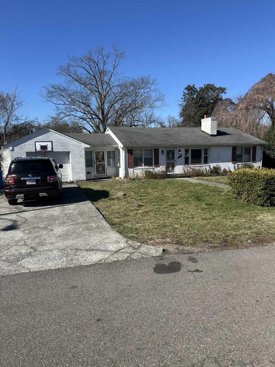 ranch-style house with an attached garage, driveway, a chimney, and a front lawn