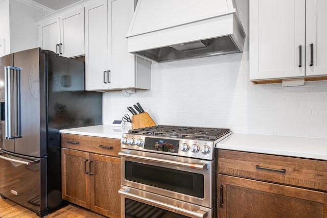 1042 Round Meadow Dr, Christiansburg, VA 24073 - kitchen featuring stainless steel appliances, custom exhaust hood, light wood-style flooring, backsplash, and light countertops