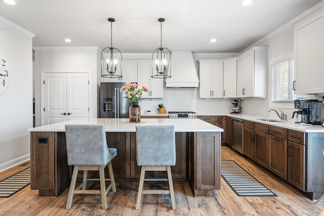 1042 Round Meadow Dr, Christiansburg, VA 24073 - kitchen with appliances with stainless steel finishes, premium range hood, a kitchen island, light wood finished floors, and light countertops