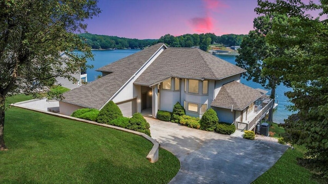 tudor home with concrete driveway, an attached garage, a front yard, and stucco siding