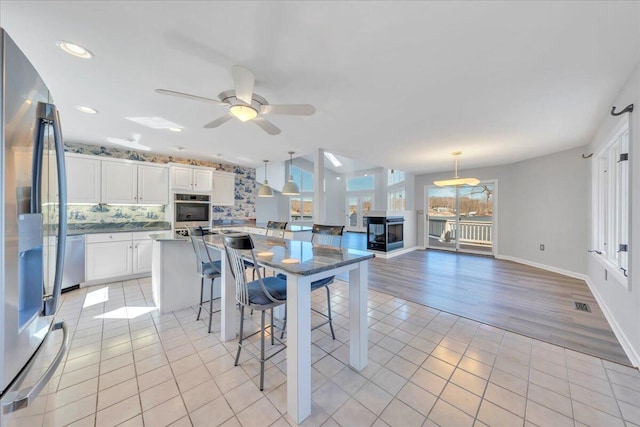 kitchen with visible vents, a ceiling fan, tasteful backsplash, stainless steel appliances, and light tile patterned flooring