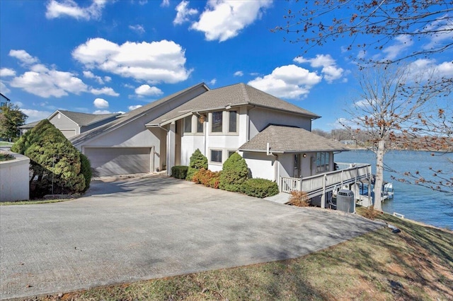 view of front of home featuring stucco siding, a water view, driveway, cooling unit, and an attached garage