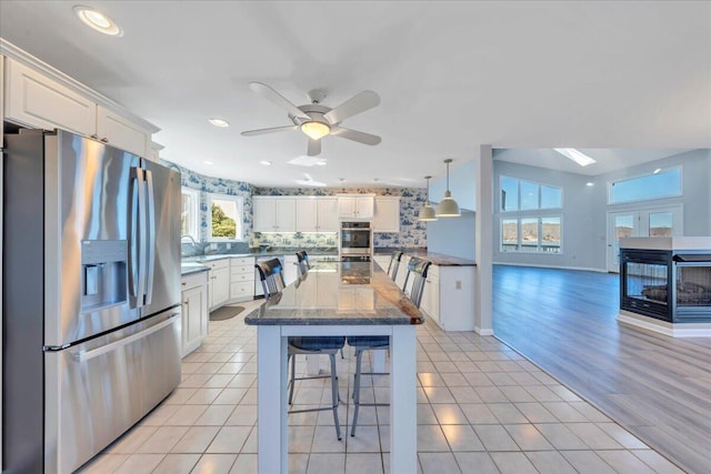 kitchen featuring white cabinetry, a breakfast bar area, light tile patterned floors, and appliances with stainless steel finishes