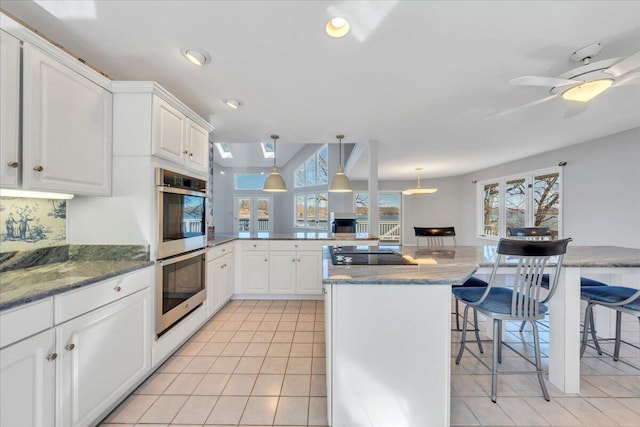 kitchen featuring white cabinetry, a peninsula, a breakfast bar, and stainless steel double oven