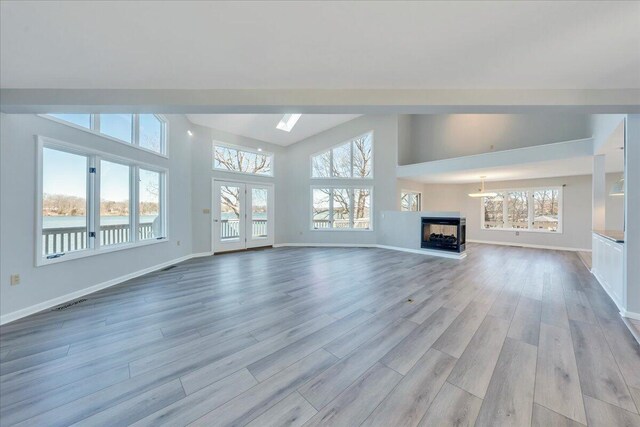 unfurnished living room featuring a multi sided fireplace, visible vents, baseboards, and light wood-style floors