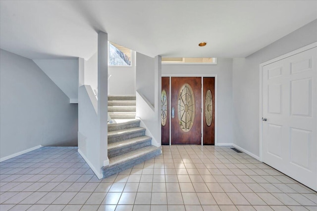 entryway with light tile patterned floors, visible vents, baseboards, and stairs