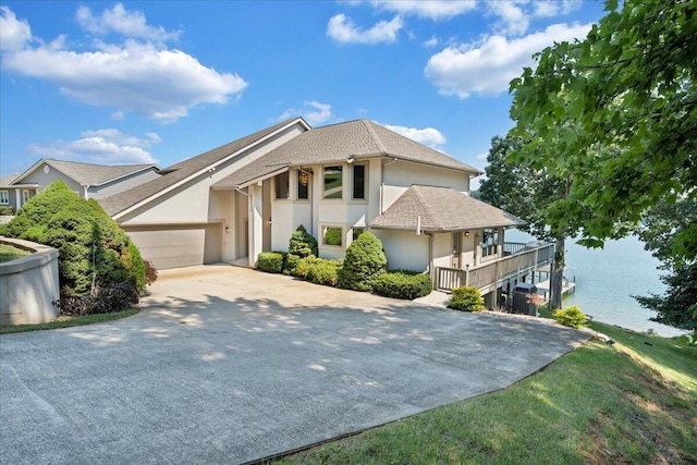 view of front of home with stucco siding, a water view, an attached garage, and driveway