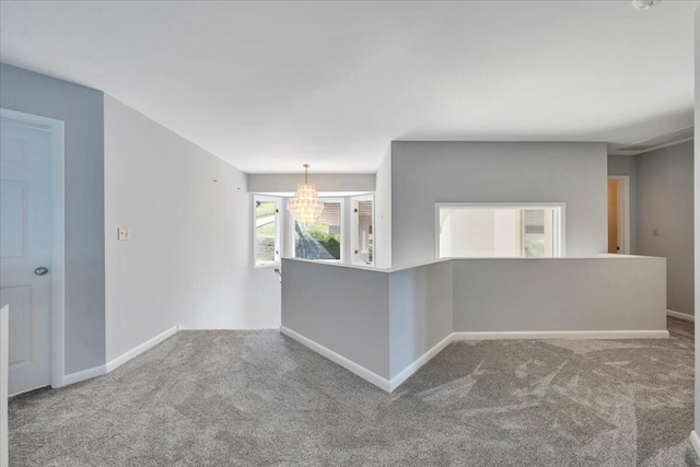 unfurnished room featuring baseboards, carpet, and an inviting chandelier