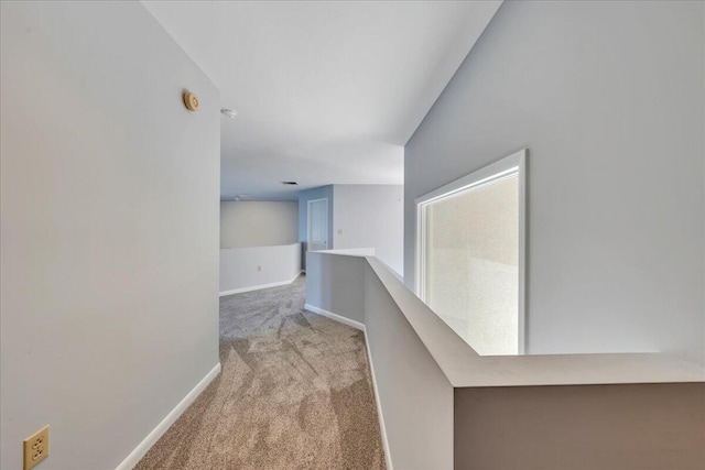 corridor with baseboards, an upstairs landing, and carpet