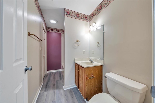 bathroom featuring toilet, vanity, baseboards, and wood finished floors