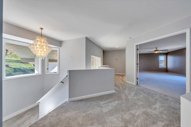 unfurnished room featuring ceiling fan with notable chandelier, baseboards, and carpet floors