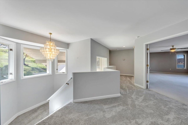 carpeted empty room with an inviting chandelier, a healthy amount of sunlight, and baseboards