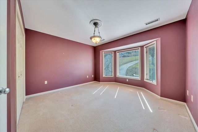 unfurnished room featuring visible vents, light colored carpet, and baseboards