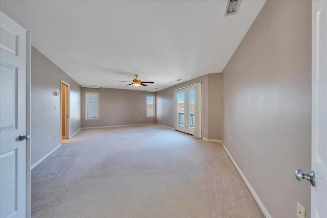 spare room featuring visible vents, a ceiling fan, baseboards, and light carpet