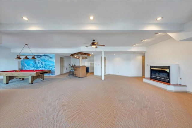 rec room with recessed lighting, a fireplace with raised hearth, light colored carpet, and a ceiling fan