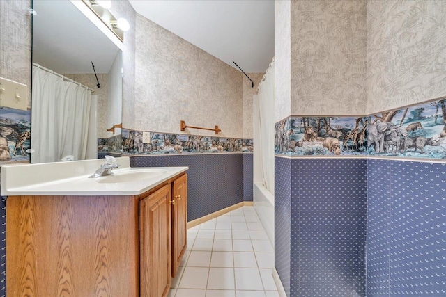 bathroom featuring tile patterned floors, shower / bathtub combination with curtain, wallpapered walls, baseboards, and vanity