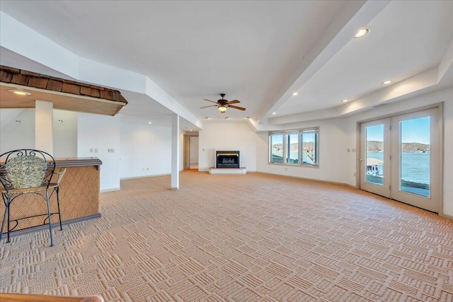 living room with a fireplace with raised hearth, baseboards, light carpet, recessed lighting, and a ceiling fan