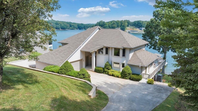 tudor house featuring stucco siding, a front lawn, driveway, an attached garage, and central AC unit