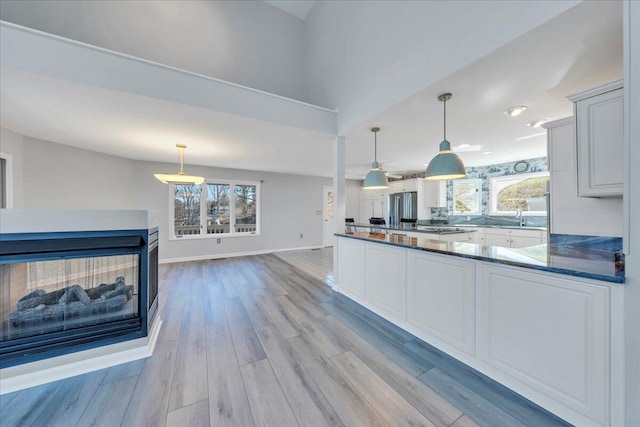 kitchen with stainless steel fridge with ice dispenser, a healthy amount of sunlight, light wood-type flooring, and baseboards