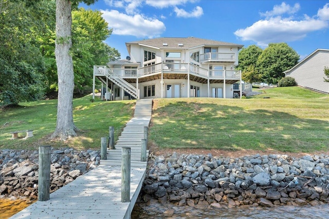 rear view of property featuring a lawn, a wooden deck, stairs, and stucco siding