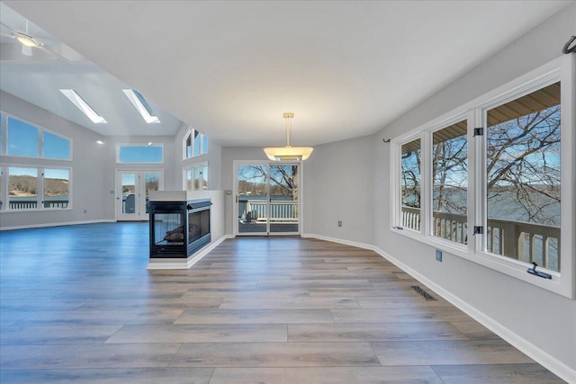unfurnished living room with visible vents, a skylight, baseboards, and wood finished floors