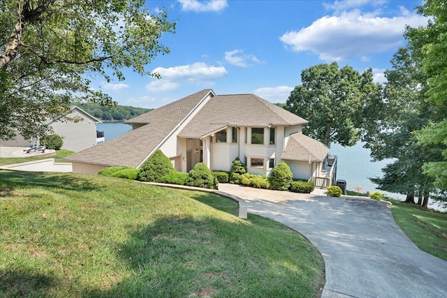 view of front of home featuring a front lawn, concrete driveway, a water view, and stucco siding