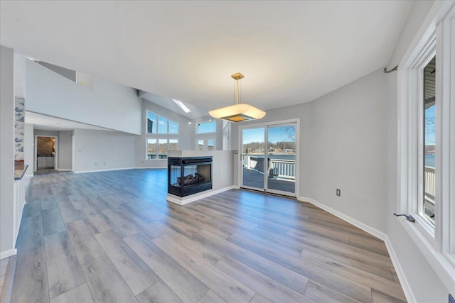 unfurnished living room with a multi sided fireplace, plenty of natural light, and wood finished floors