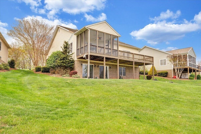 back of house featuring a sunroom, a yard, a ceiling fan, brick siding, and a wooden deck