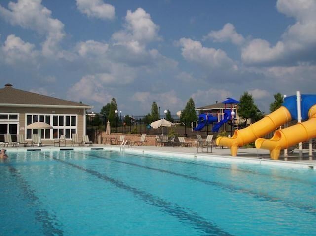 community pool with playground community, a patio area, a water slide, and fence