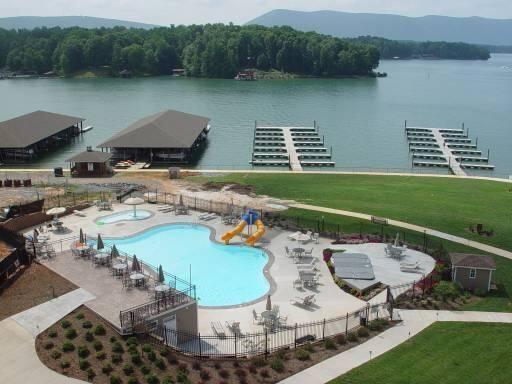 pool with a water view, a water slide, fence, and a patio area