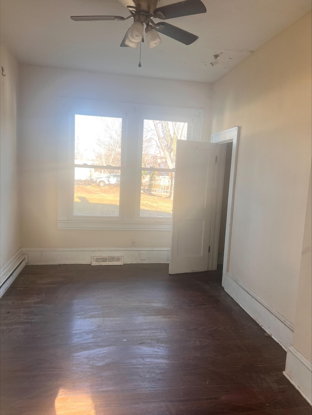 unfurnished room with visible vents, a ceiling fan, and dark wood-style flooring