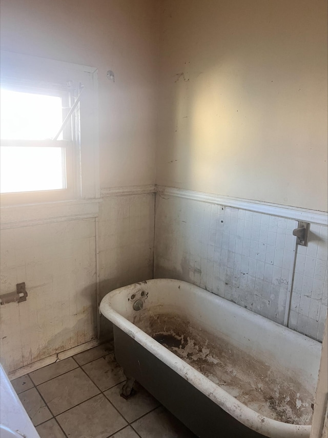 bathroom with tile patterned flooring, a soaking tub, and wainscoting
