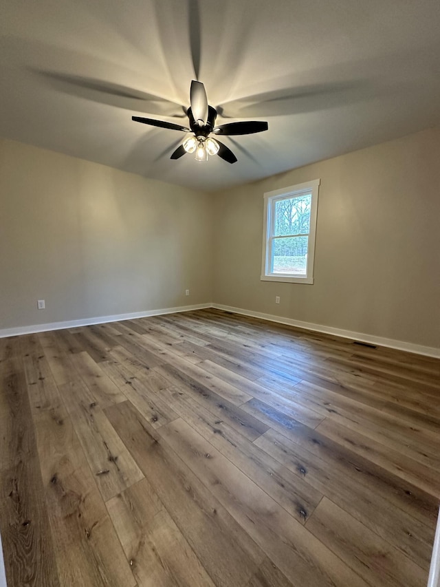empty room featuring ceiling fan, wood-type flooring, and baseboards