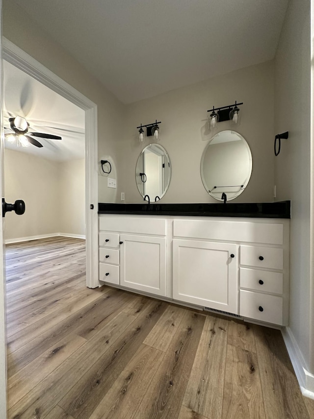 bathroom featuring ceiling fan, vanity, wood finished floors, and baseboards