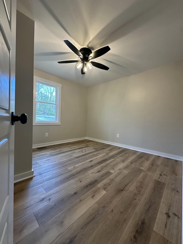 spare room featuring hardwood / wood-style floors, baseboards, and a ceiling fan