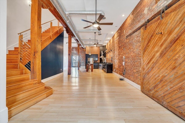 133 Norfolk Ave SW, Roanoke, VA 24011 - unfurnished living room with brick wall, stairs, a ceiling fan, light wood-style flooring, and baseboards