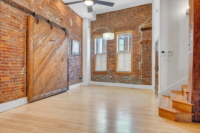 133 Norfolk Ave SW, Roanoke, VA 24011 - unfurnished room with brick wall, a ceiling fan, hardwood / wood-style floors, baseboards, and a barn door