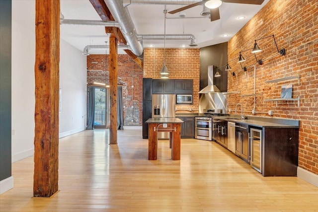 133 Norfolk Ave SW, Roanoke, VA 24011 - kitchen featuring stainless steel appliances, wall chimney exhaust hood, brick wall, beverage cooler, and baseboards