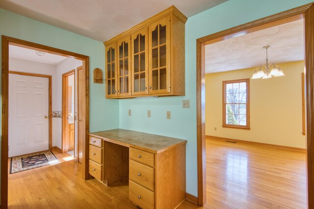 195 Showalter Rd NW, Willis, VA 24380 - kitchen with light wood finished floors, glass insert cabinets, a chandelier, and light countertops