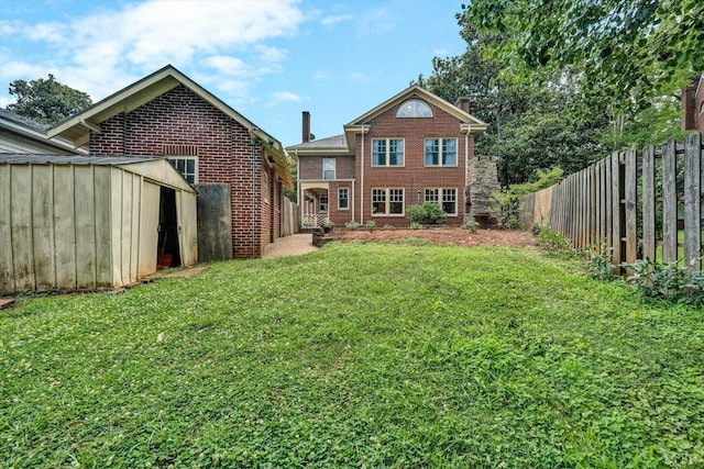 rear view of property featuring brick siding, fence, and a lawn